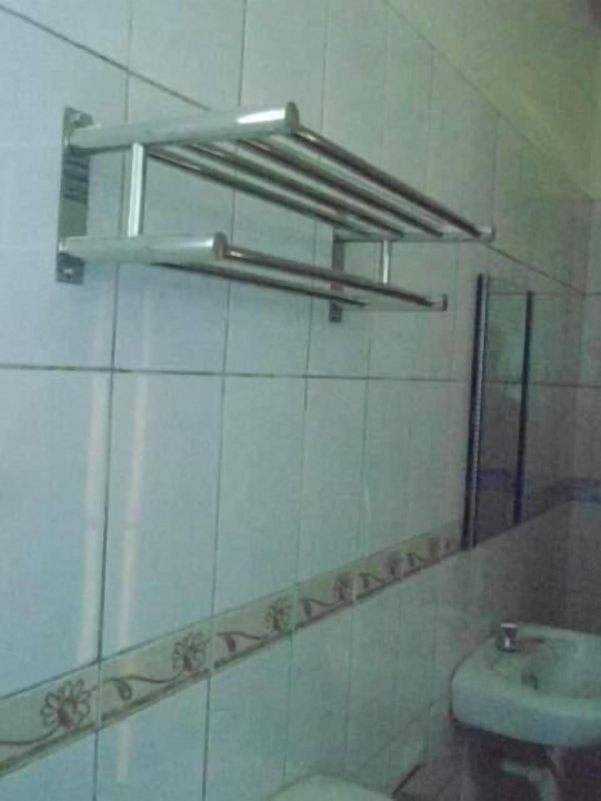 Un baño con paredes de azulejos blancos, un perchero de metal, un lavabo y una decoración de azulejos en el borde.