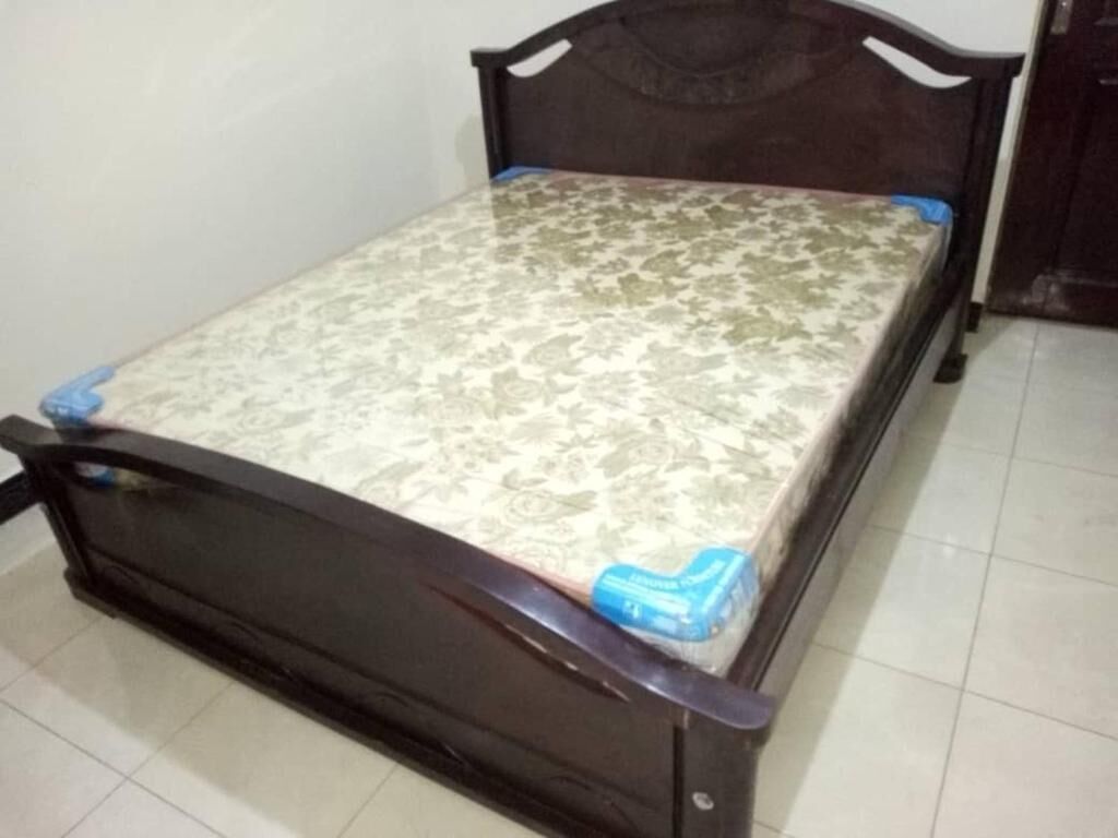 Una cama con un colchón estampado y un cabecero de madera oscura.