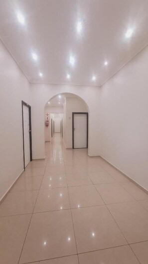 A corridor with a tiled floor, white walls, and doors on both sides. - Bayside Lodge Empangeni (Empangeni)
