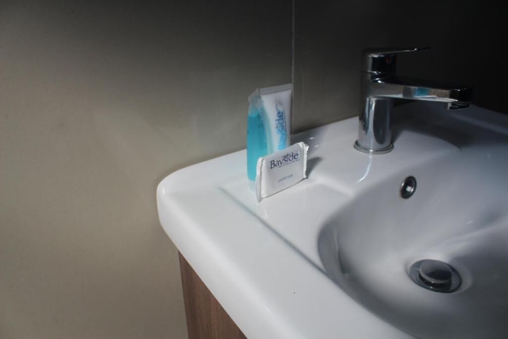 A bathroom sink with a Bayside soap dispenser and a chrome faucet.