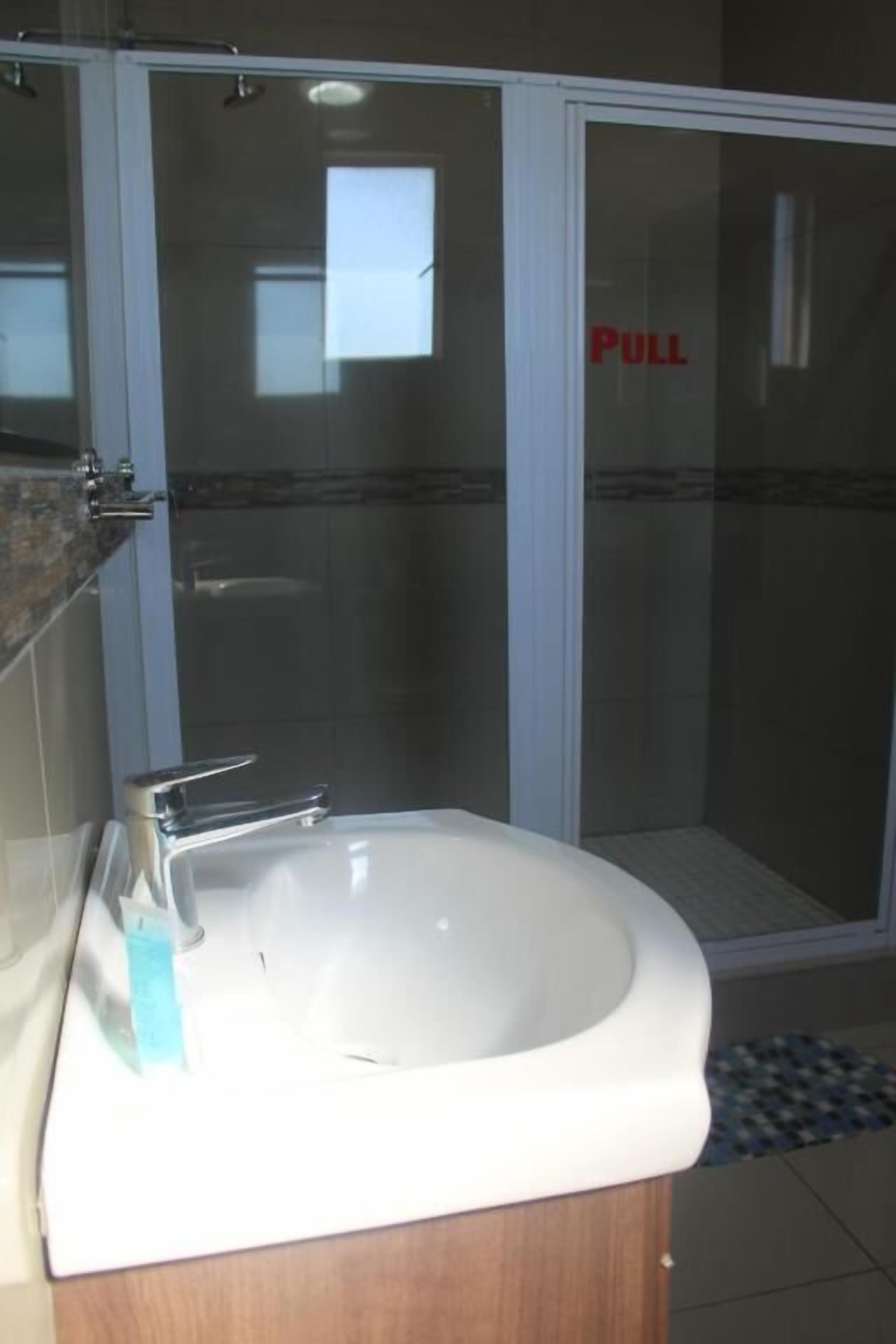 A bathroom with a white sink, a mirror, and a glass shower enclosure.