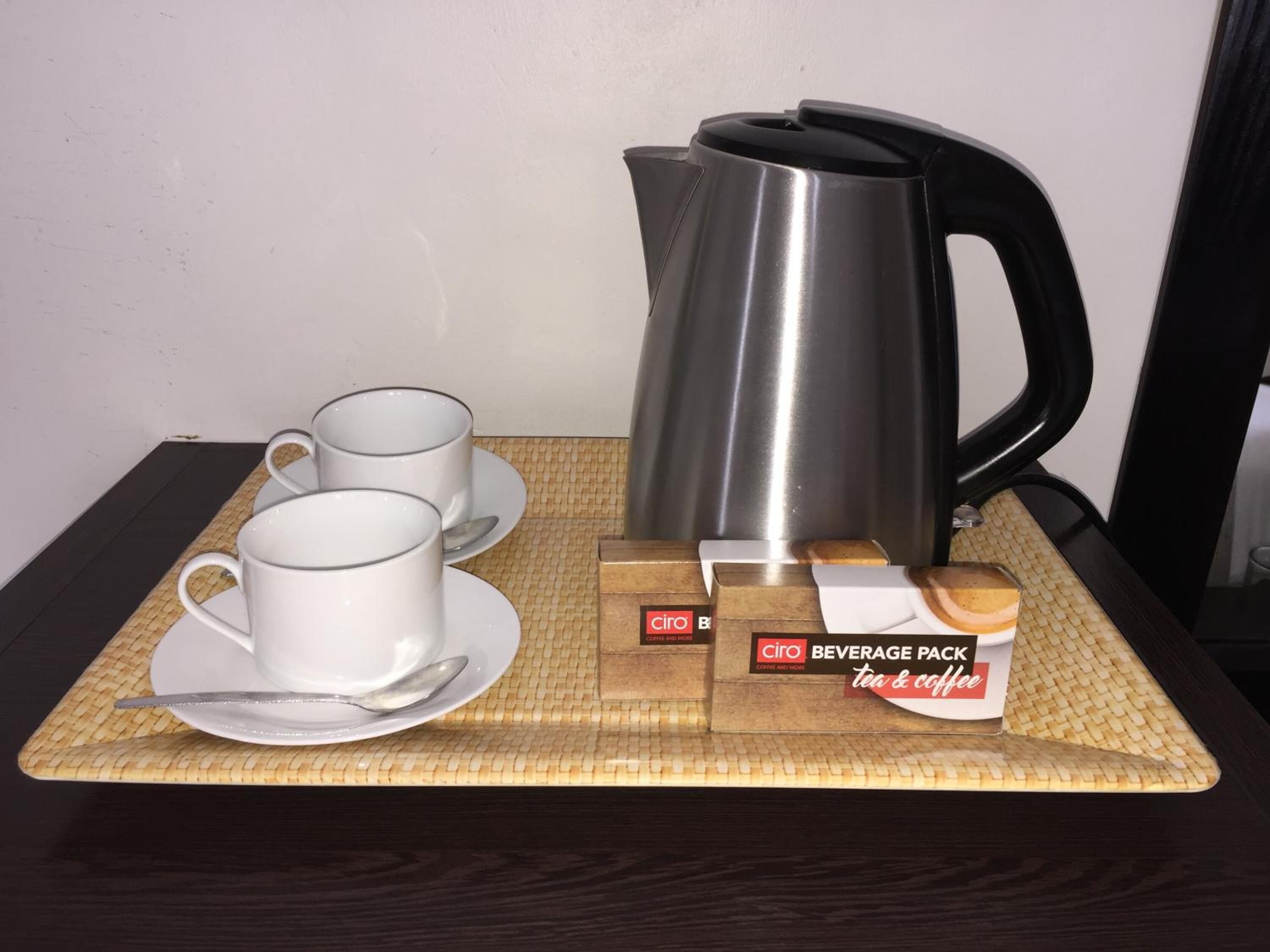 A tray with two white cups, a silver teapot, and three beverage packs labeled "Ciro Beverage Pack tea & coffee" on a woven mat.