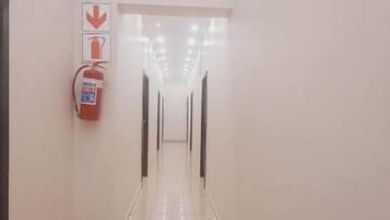 A long, well-lit corridor with a fire extinguisher on the left and a door at the end.