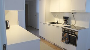 A modern kitchen with white cabinetry, a stainless steel sink, a coffee maker, and an oven. - Forenom Serviced Apartments Rovaniemi (Rovaniemi)