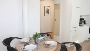 A dining area with a round table set for four, surrounded by black chairs. There is a small potted plant on the table, and a framed picture on the wall. - Forenom Serviced Apartments Rovaniemi (Rovaniemi)
