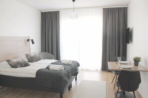 A modern hotel room with a bed, bedside table, and a desk with a chair. - Forenom Serviced Apartments Rovaniemi (Rovaniemi)