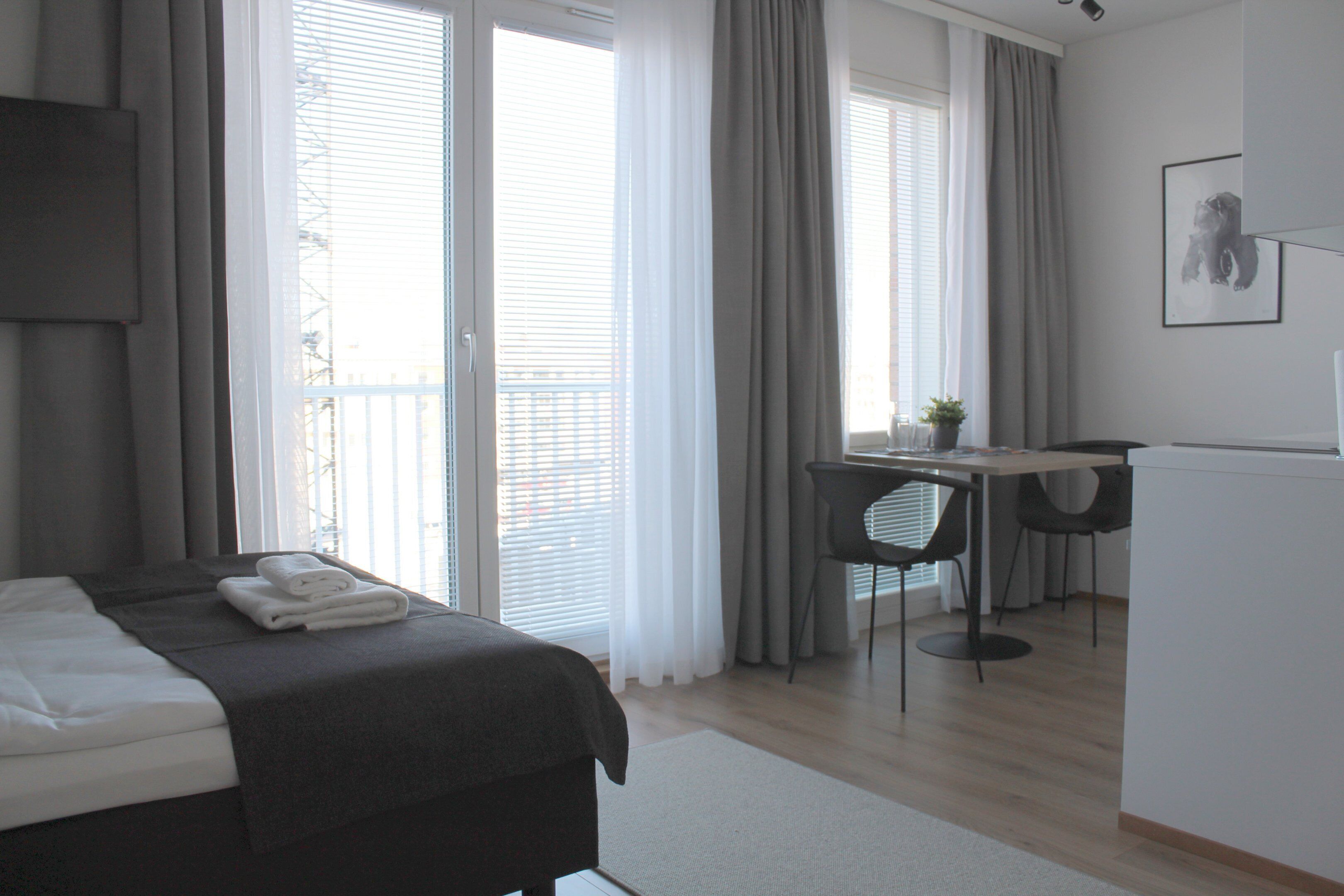 A modern hotel room with a bed, a desk, and a chair.