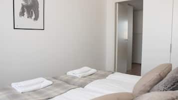 A bedroom with two beds, a framed picture on the wall, and a door leading to another room.