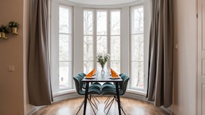 A dining area with a round table, chairs, and a window with curtains. - Forenom Serviced apartmentsHelsinkiTöölö (Helsinki)