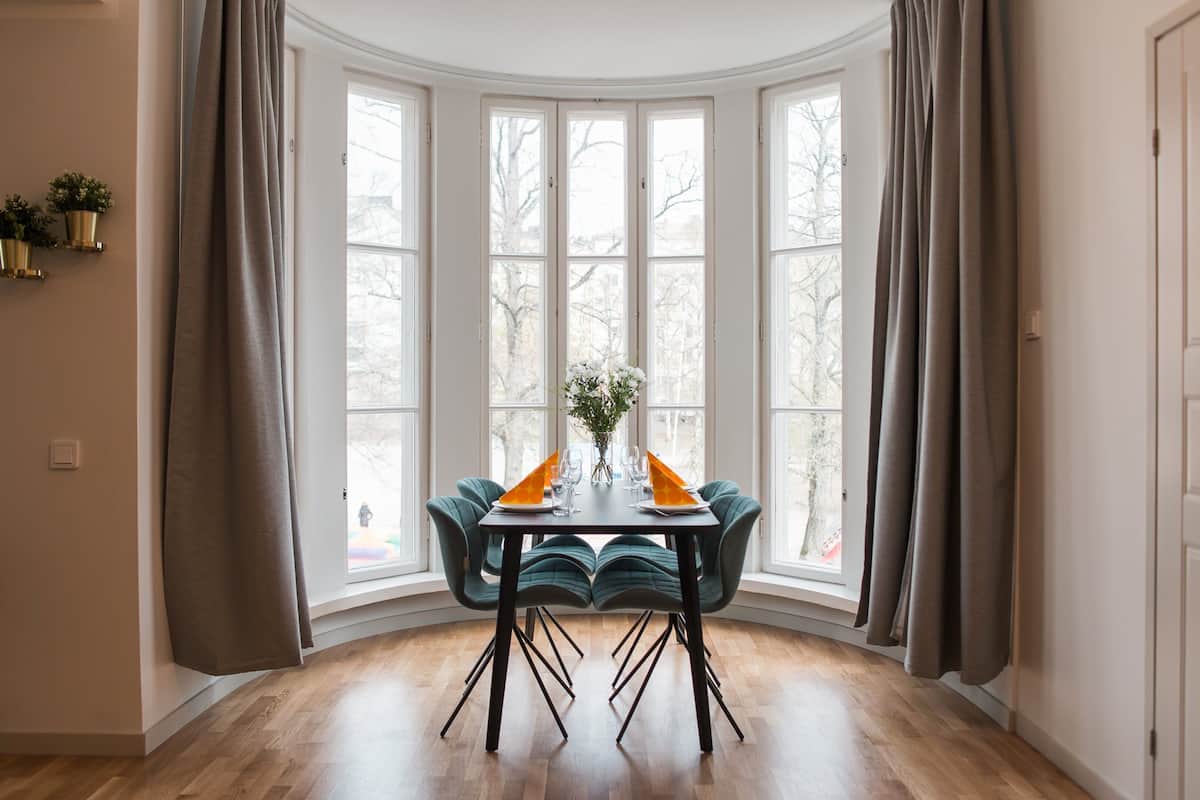 Un coin repas avec une table ronde, des chaises et une fenêtre avec des rideaux.