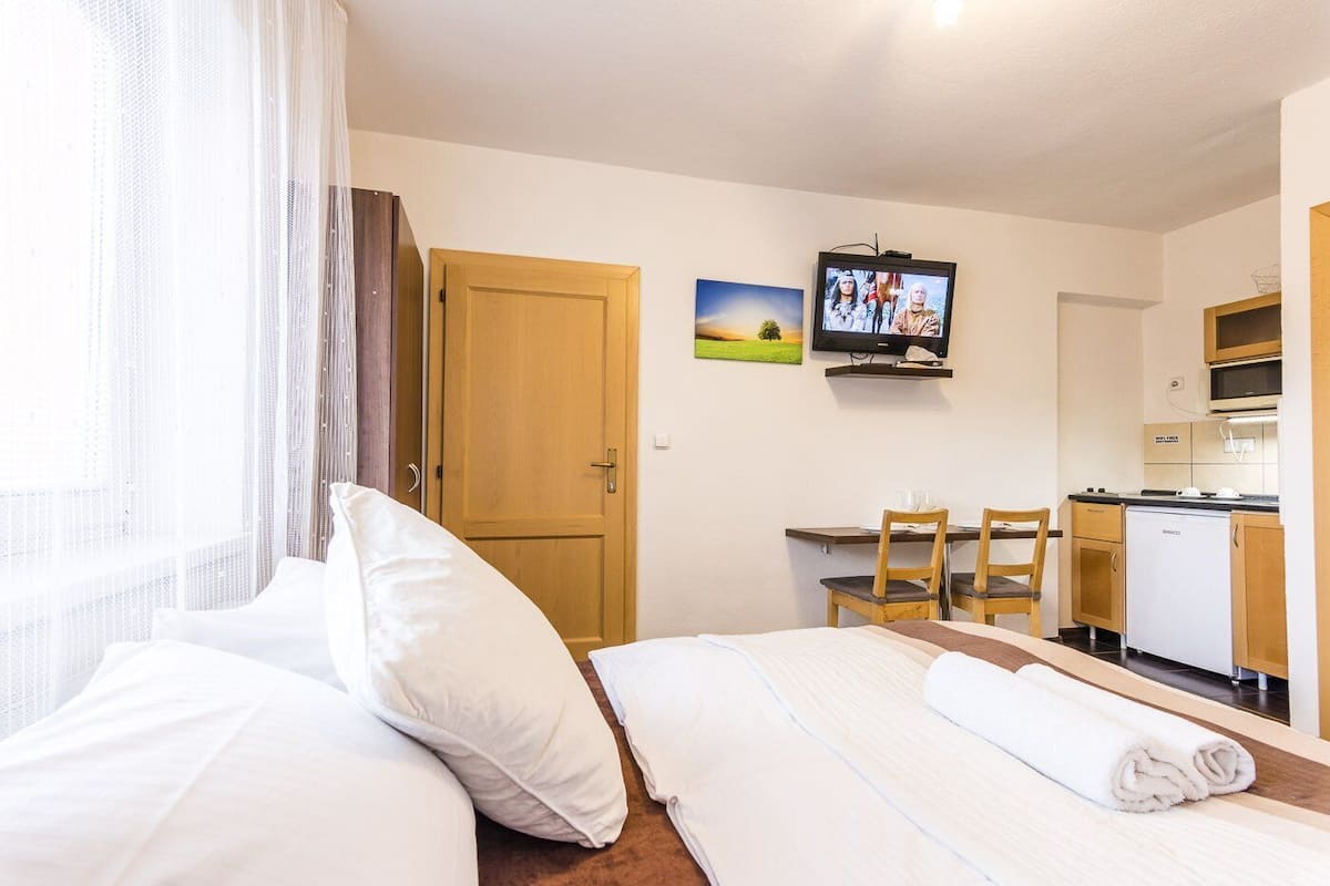 Habitación de hotel con cama, escritorio, televisor, zona de cocina y puerta.