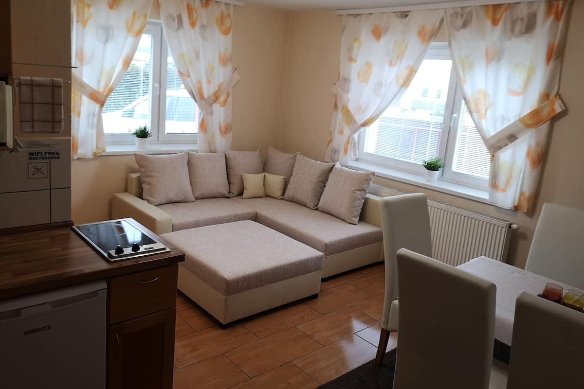 Una sala moderna con un sofá seccional, una mesa de comedor y una zona de cocina con lavavajillas.