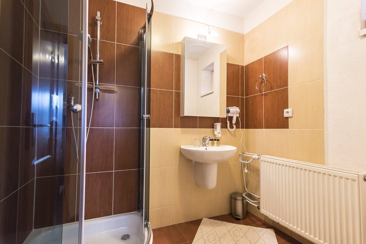 A modern bathroom with a glass shower enclosure, a sink, and a mirror.