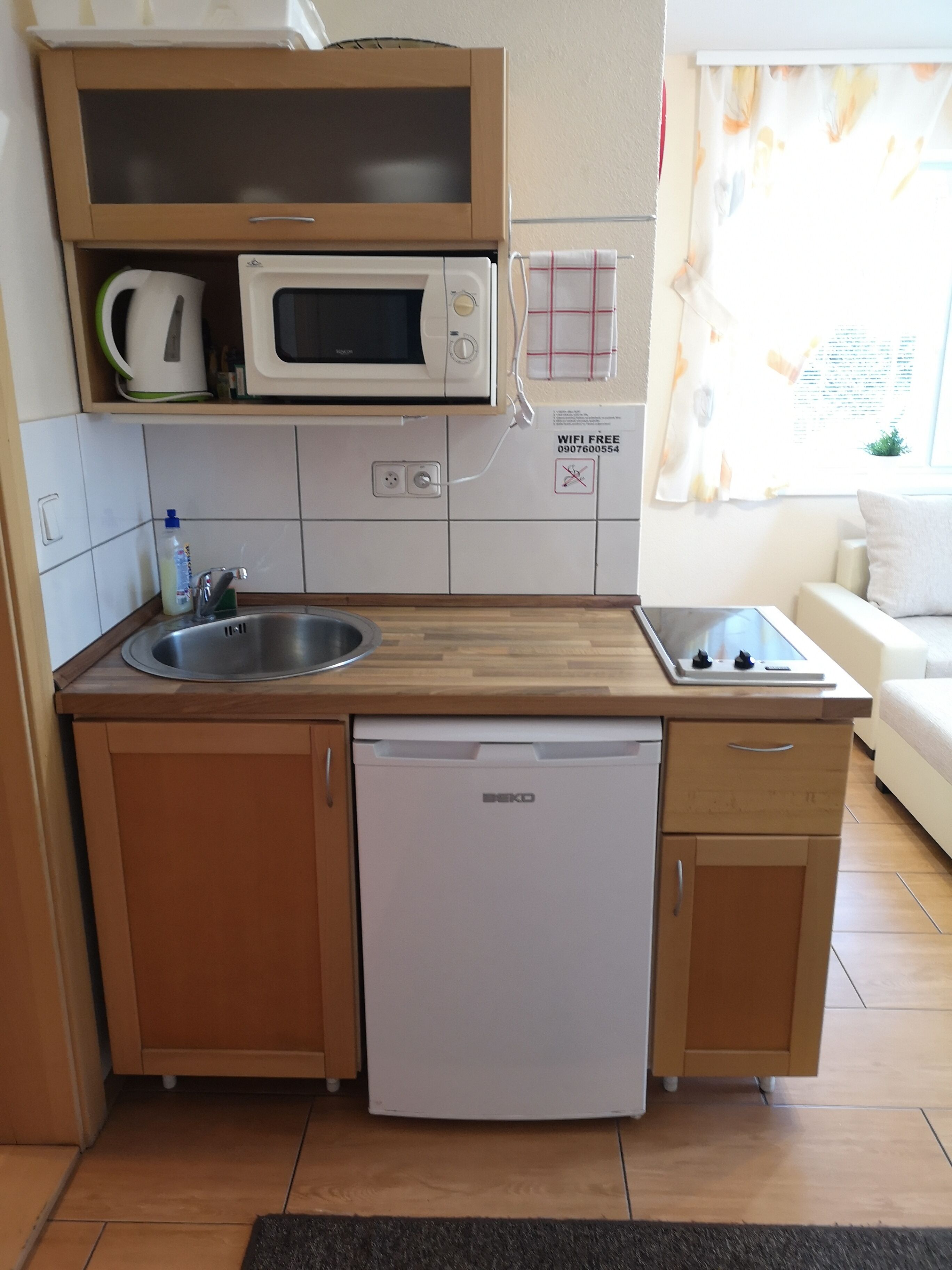 Una cucina compatta con forno a microonde integrato, lavello e lavastoviglie.