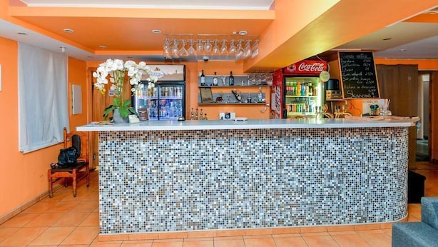 Una zona de bar con mostrador de mosaicos, estantes con botellas y un refrigerador de Coca-Cola.