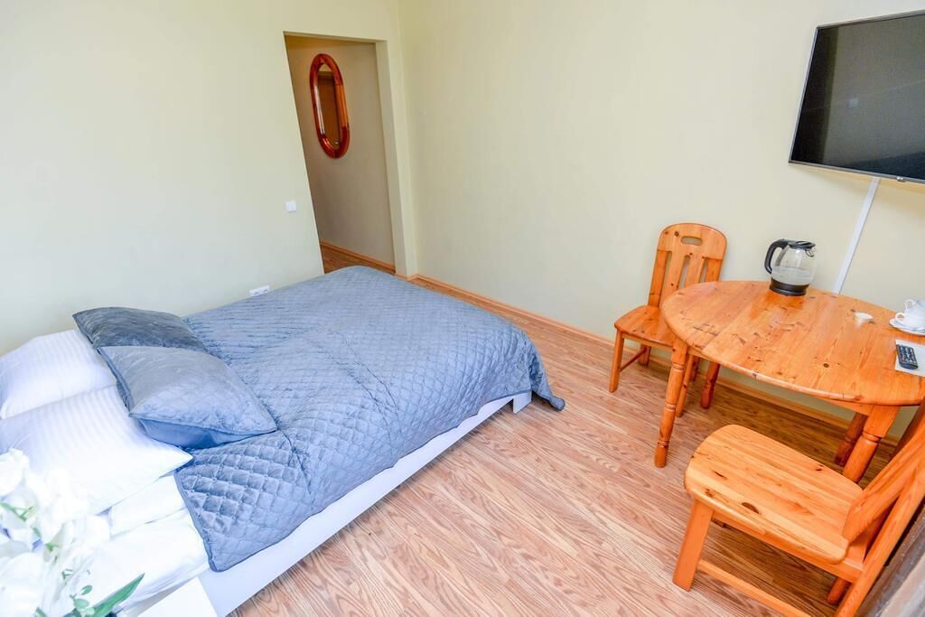 A bedroom with a bed, a wooden table, and a chair.