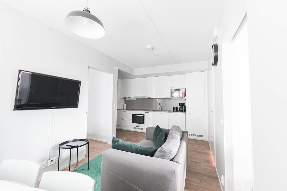 Un salon moderne avec un téléviseur à écran plat, un canapé gris et une petite table d’appoint.