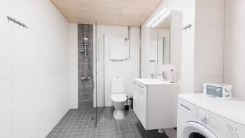 A modern bathroom with a shower, toilet, and a washing machine.
