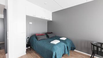 Un dormitorio moderno con cama, mesitas de noche y una silla.