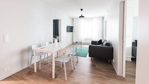 A modern, bright living space with a dining area, a sofa, and a television. - Forenom Serviced Apartments Neilikkatie (Vantaa)