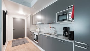 A modern kitchen with grey cabinets, a stainless steel sink, a microwave, and a coffee maker. - Forenom Serviced Apartments Neilikkatie (Vantaa)