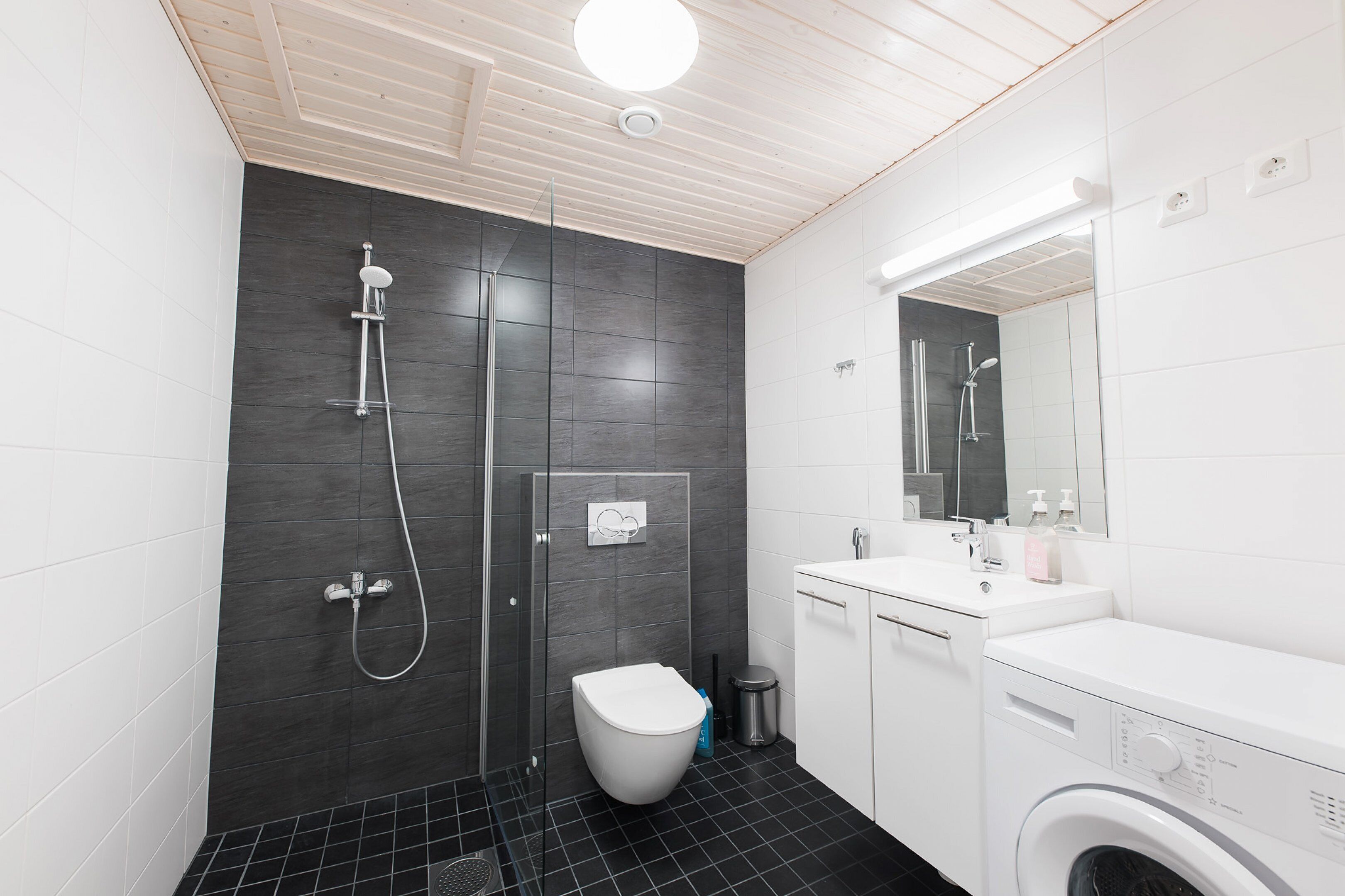 Un baño moderno con ducha, inodoro, lavamanos y lavadora.