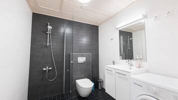 Un baño moderno con ducha, inodoro, lavamanos y lavadora.