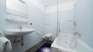 Et moderne badeværelse med vask, toilet og badekar.