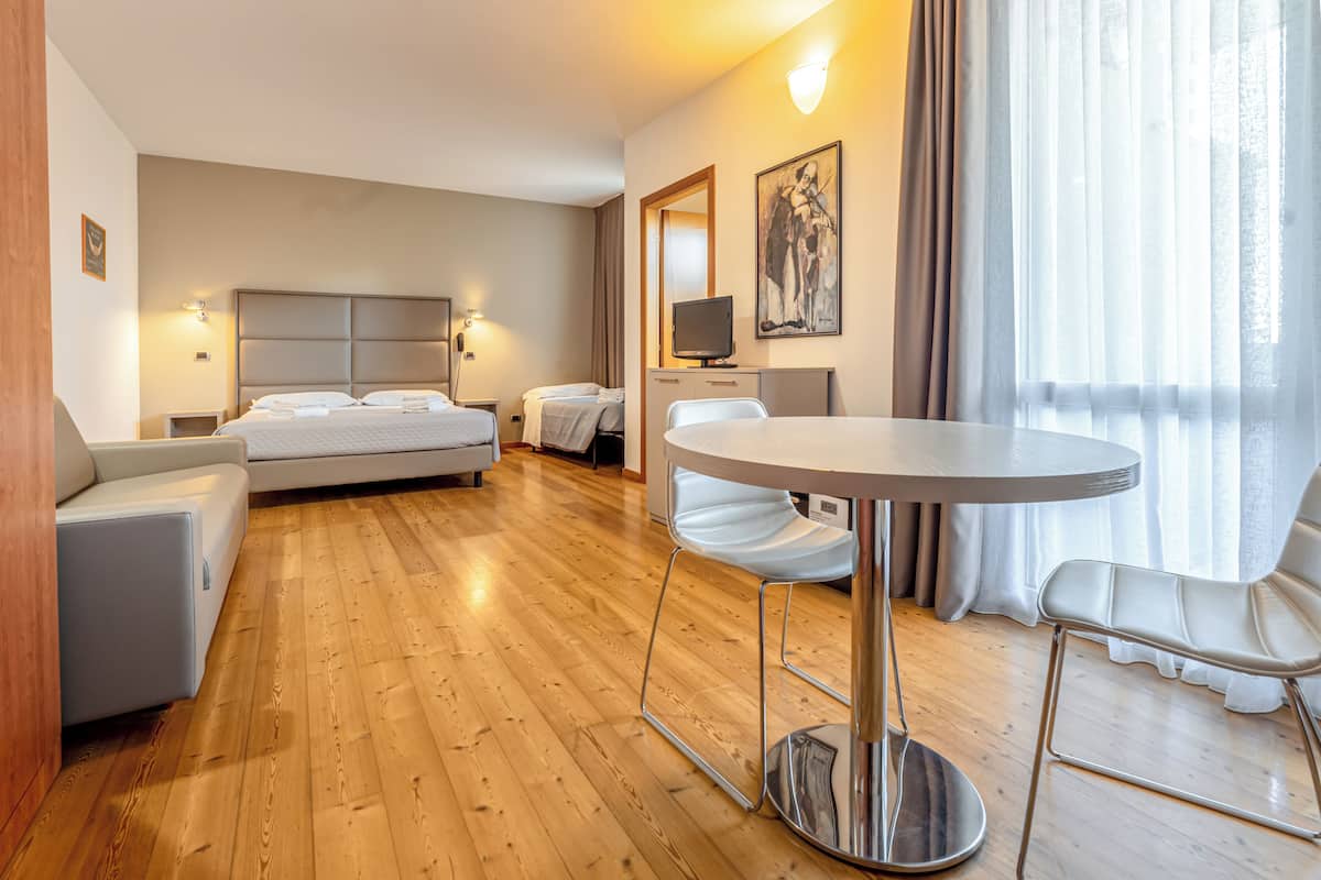 Une chambre d’hôtel avec un lit, un canapé, une table à manger et un téléviseur.