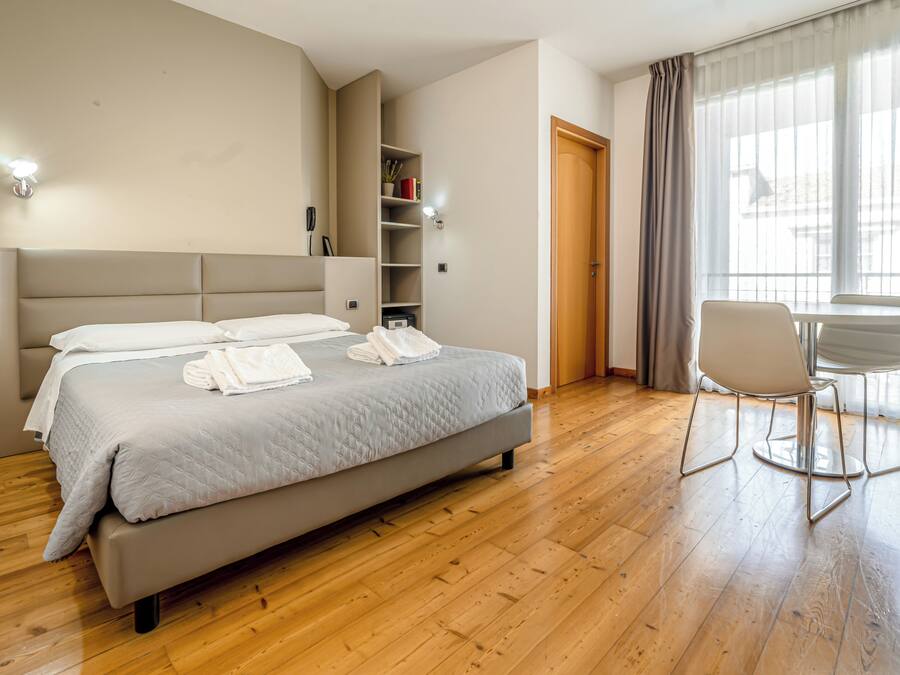 A modern hotel room with a large bed, a desk, and a chair.