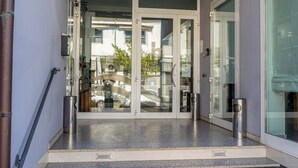 A set of stairs leading to a glass door entrance, a metal trash can, and a wall-mounted light fixture. - Rubicone Hotel (Savignano sul Rubicone)