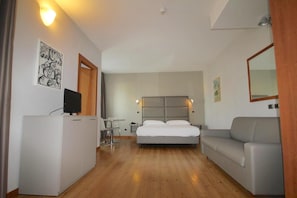 Relax in a spacious room with a large bed, sofa, and desk, perfect for work or unwinding.