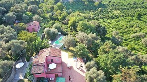 Una propiedad residencial con una casa grande, piscina y vegetación circundante.