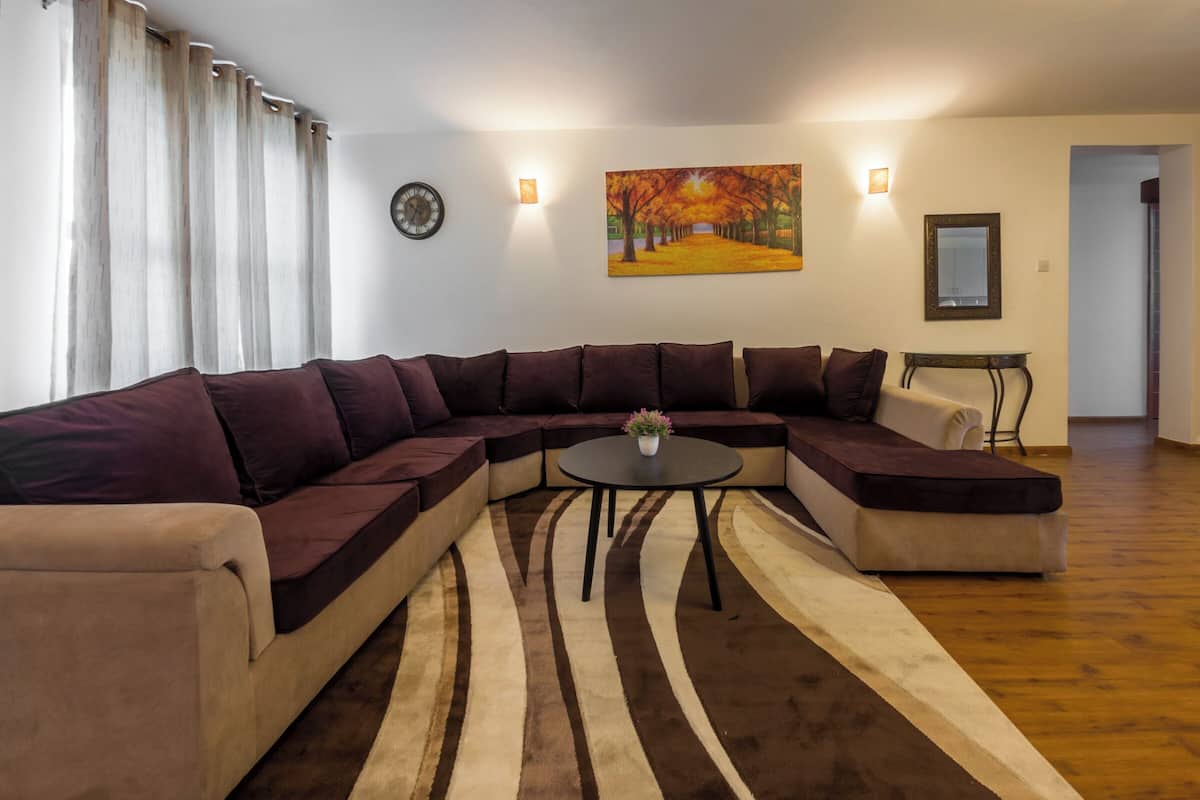 A modern living room with a sectional sofa, a round coffee table, and a decorative rug.