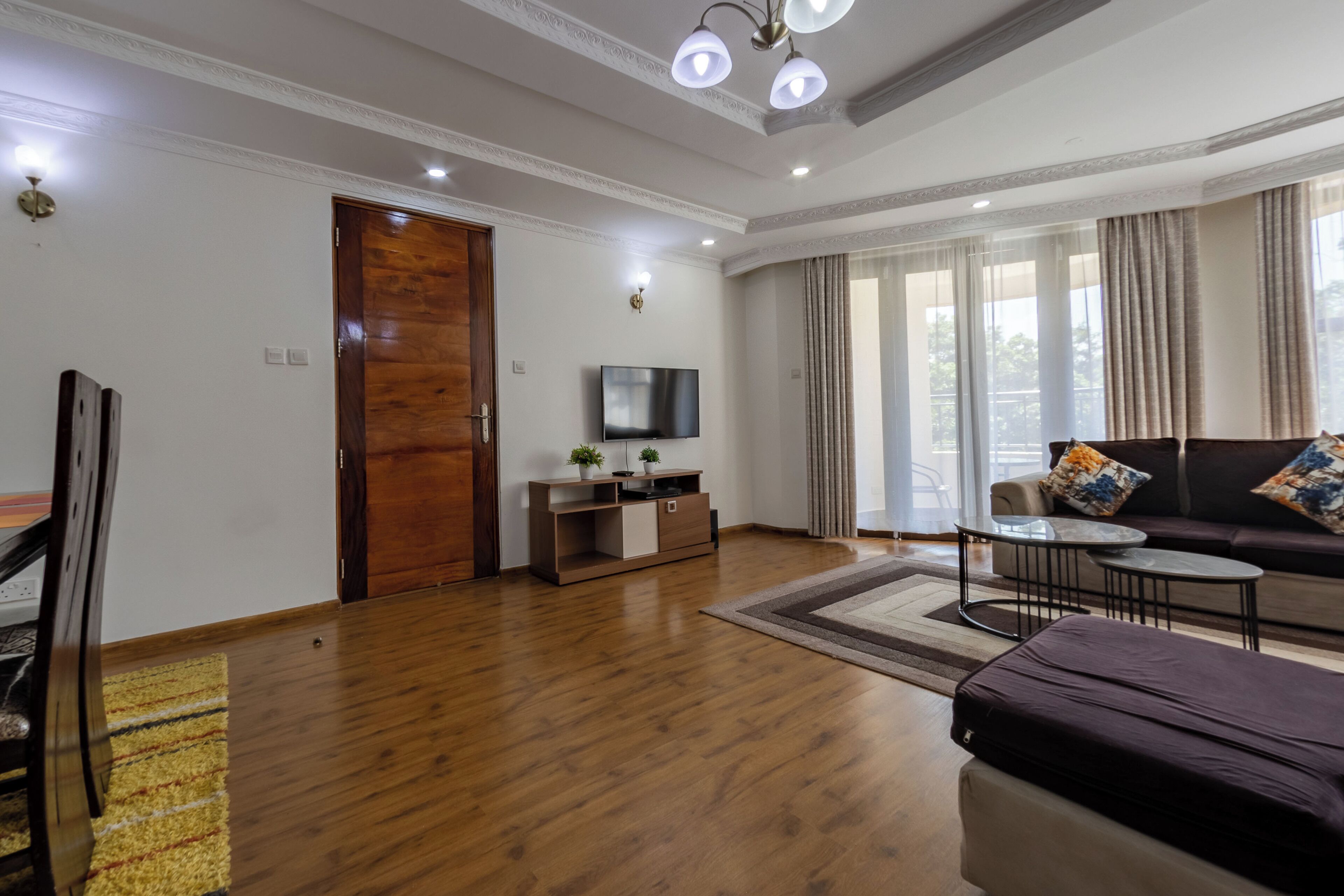A modern living room with a wooden floor, a sofa, a TV, and a small coffee table.