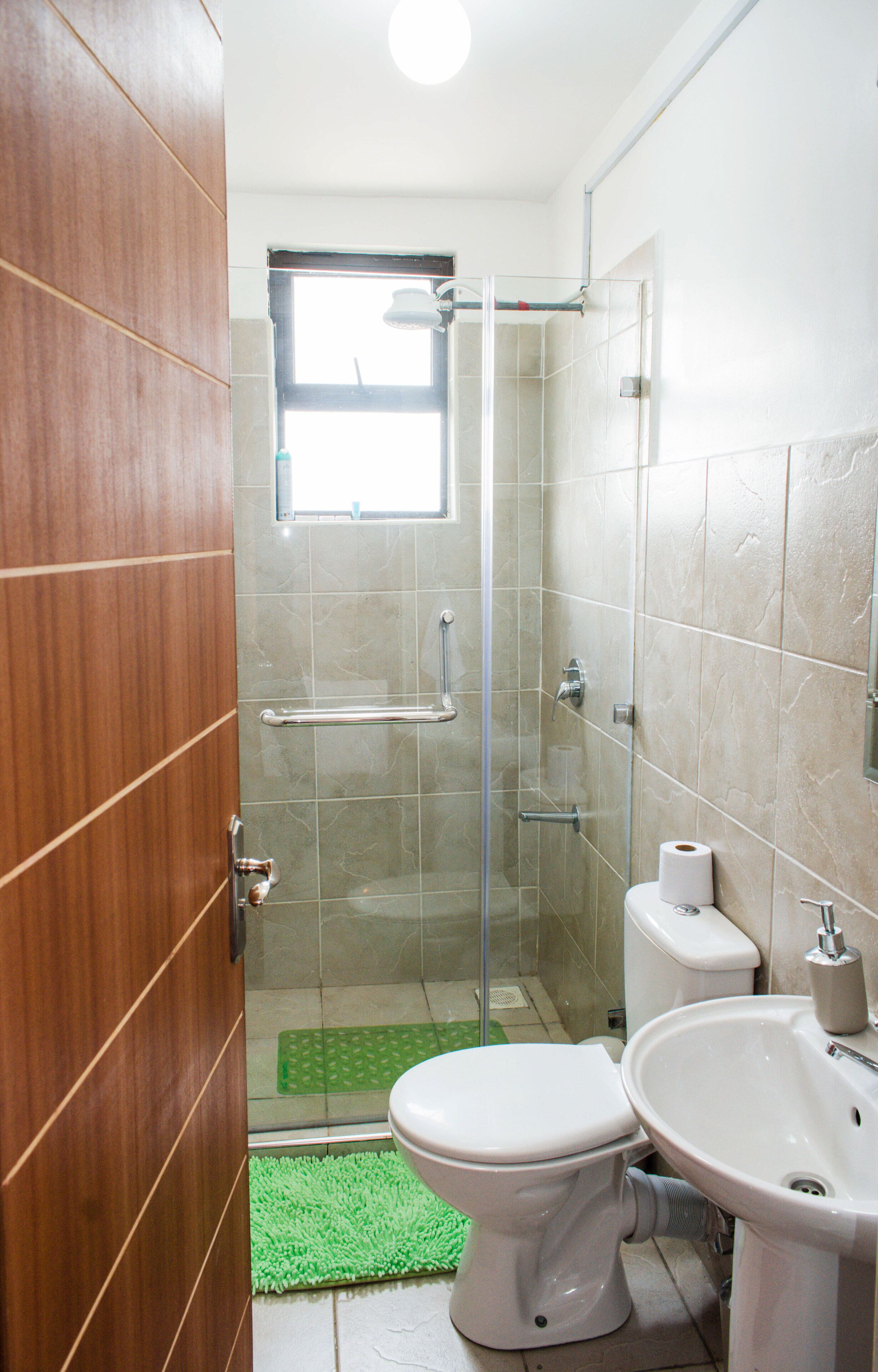 A bathroom with a glass shower enclosure, a toilet, and a sink.