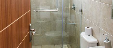 Une salle de bain avec une douche à parois en verre, des toilettes et un lavabo.