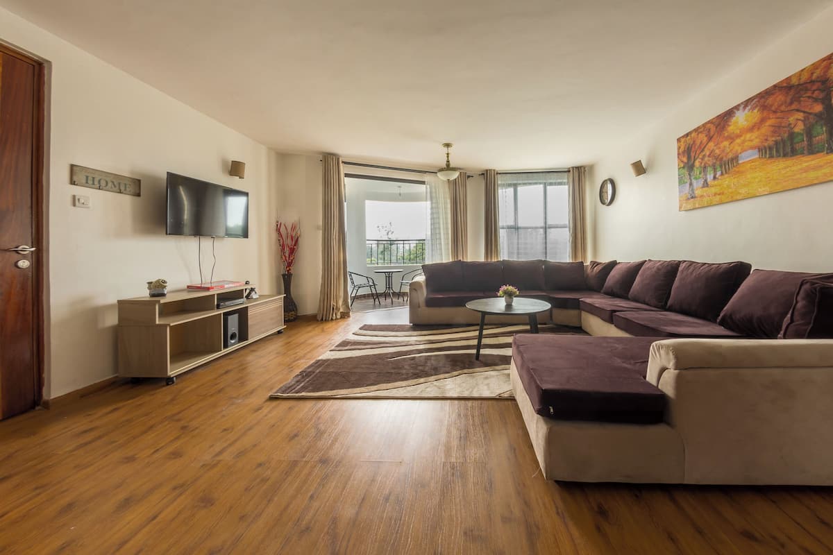 A living room with a sofa, coffee table, TV, and wooden flooring.