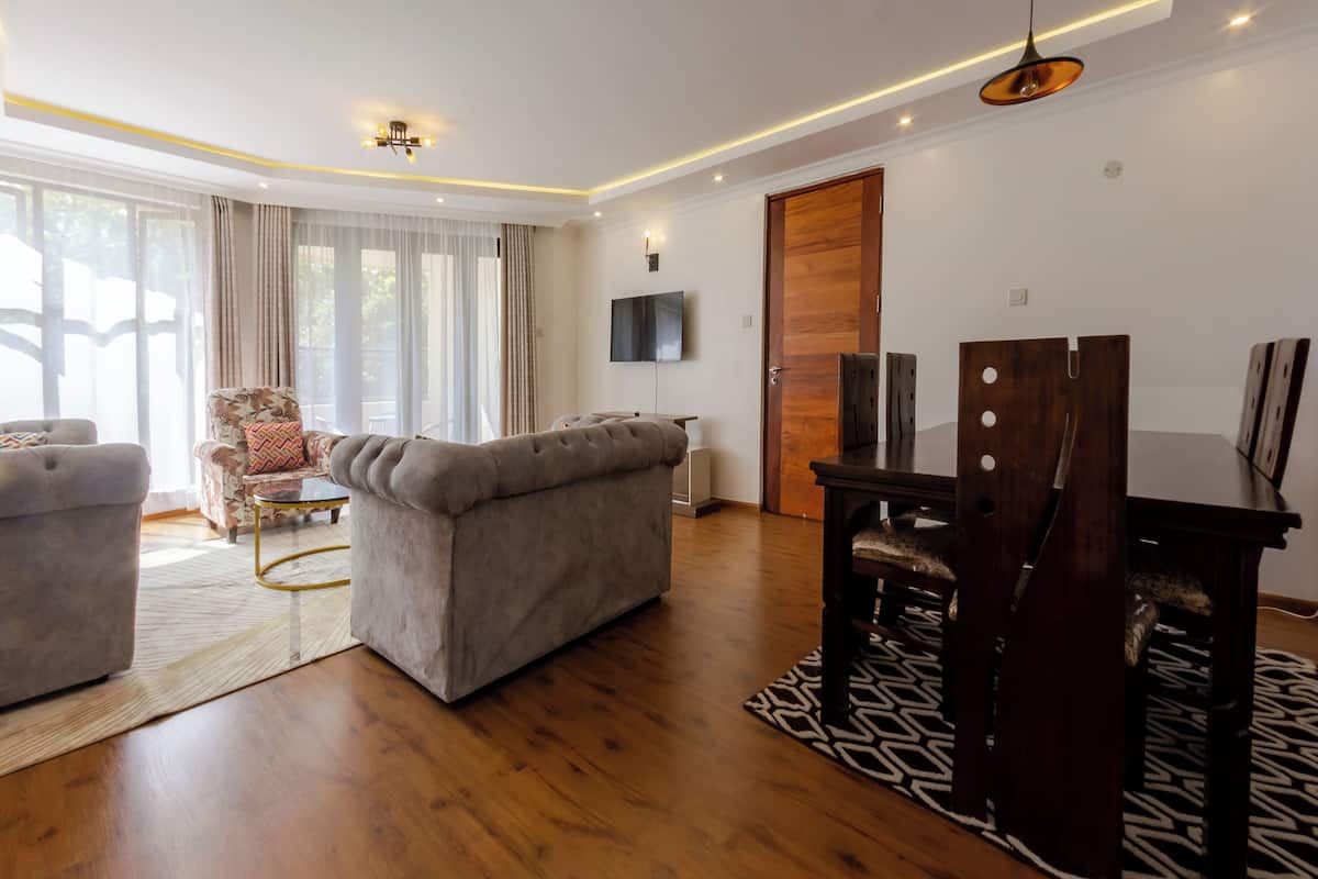 A modern living room with a sofa, armchair, and dining table.