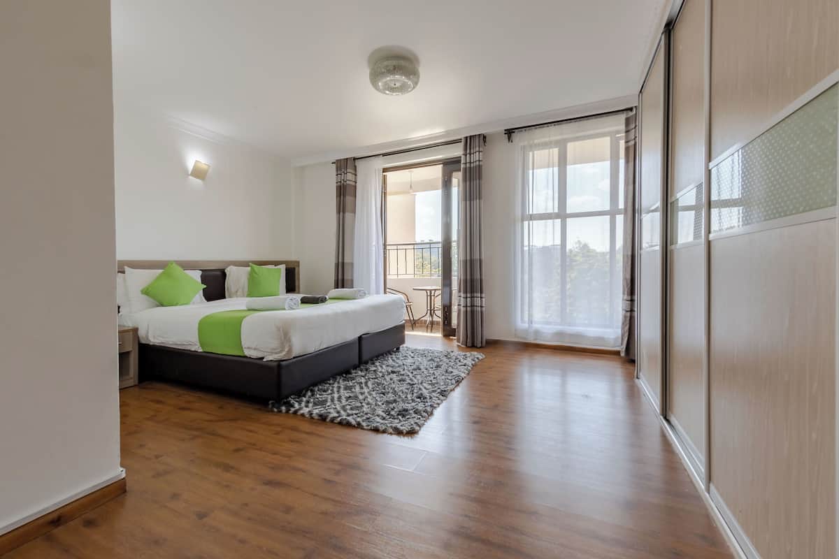 A bedroom with a bed, a small table, and a view of the outdoors.