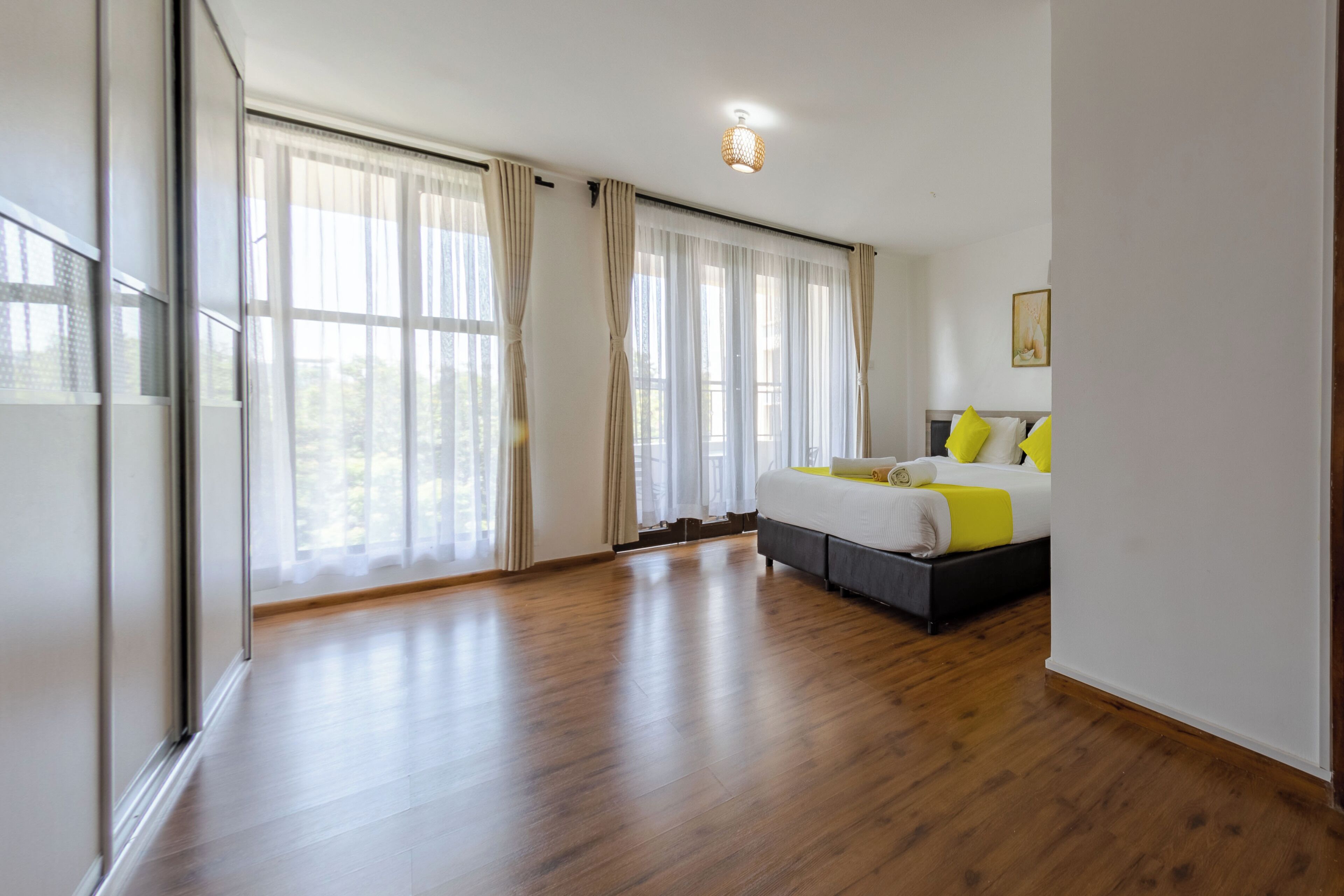 A spacious bedroom with a large bed, a wooden floor, and a view through the window.