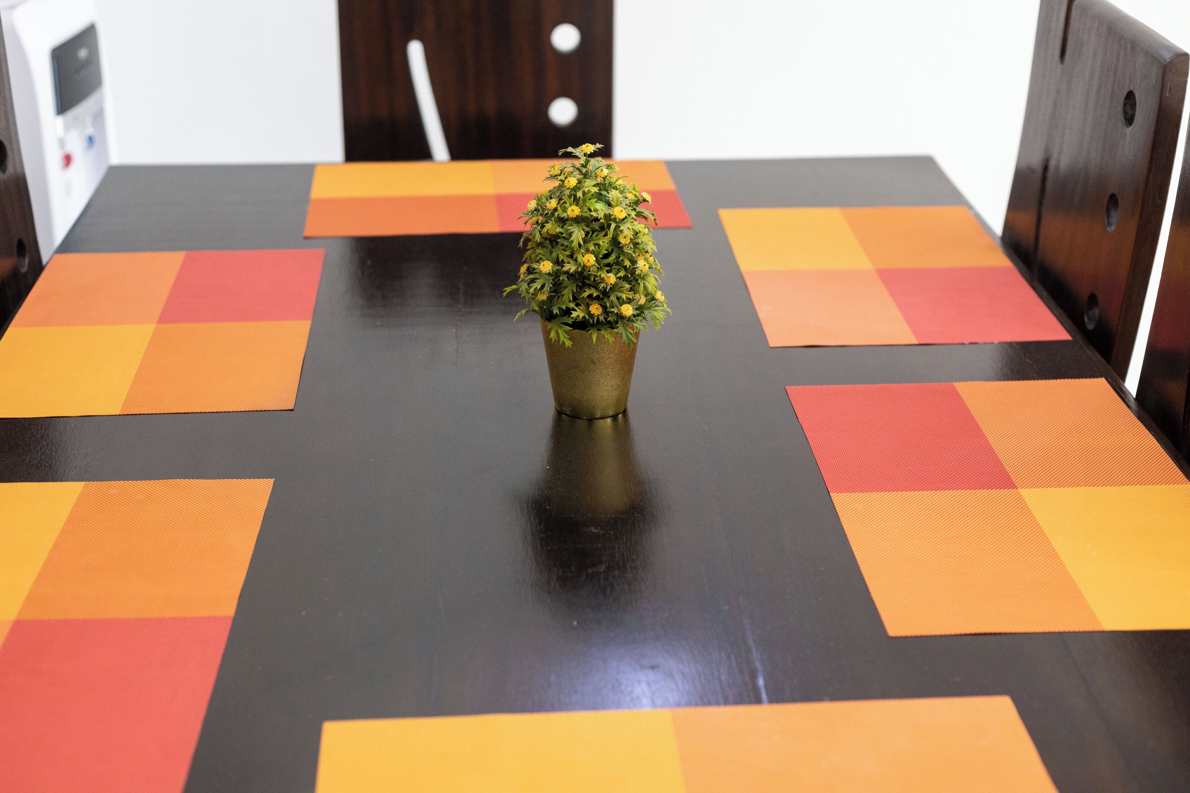 A conference table with a potted plant in the center, surrounded by a geometric patterned tablecloth.