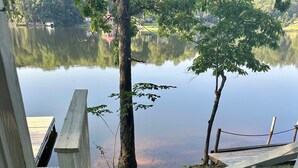 A wooden staircase leading to a dock by a calm lake, surrounded by trees and a clear sky. - Beautiful Lake Views at this Lake Front Camper on Private 25 Acre Lake (Mooresboro)
