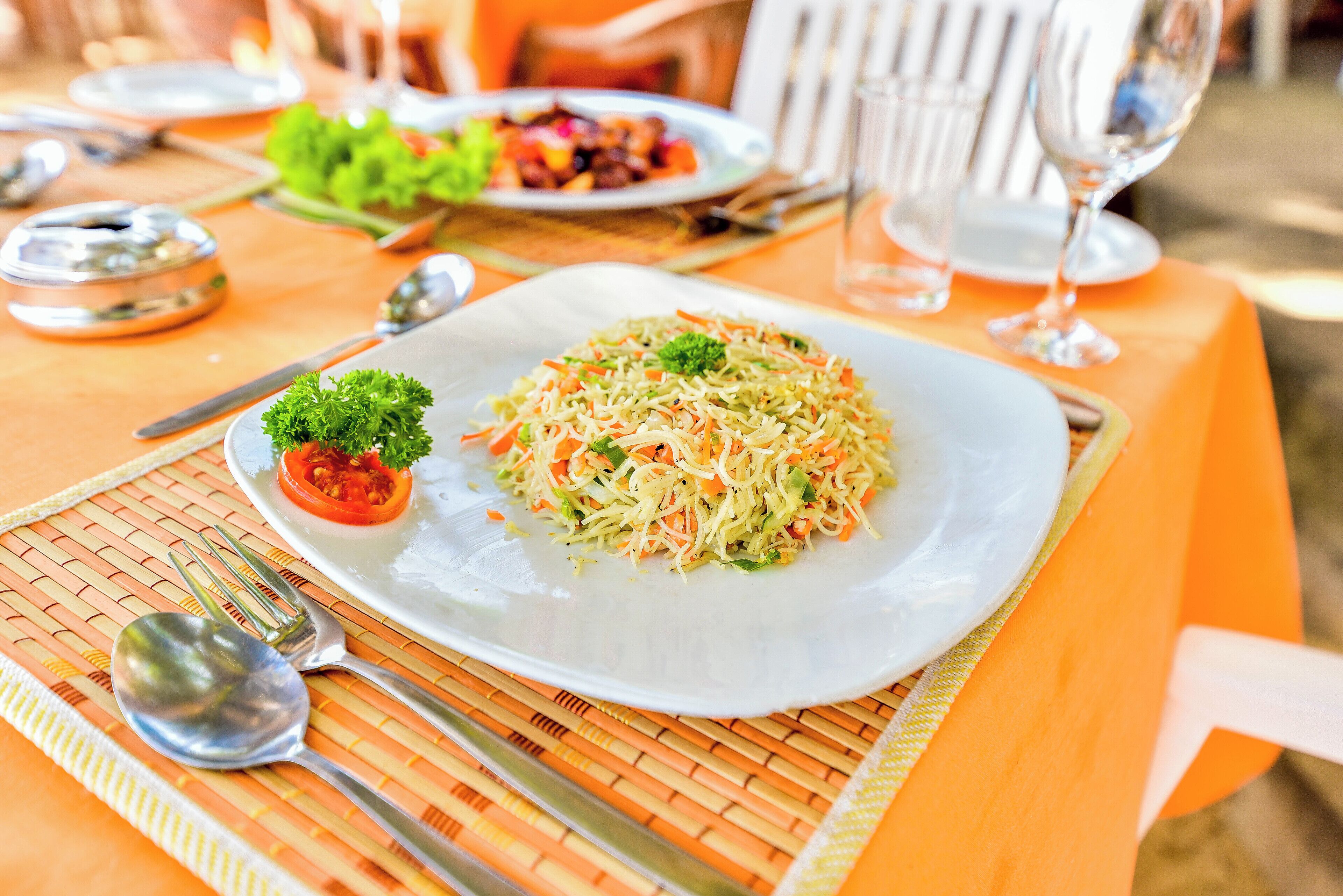 A dining table with a plate of salad, cutlery, and a glass of water.