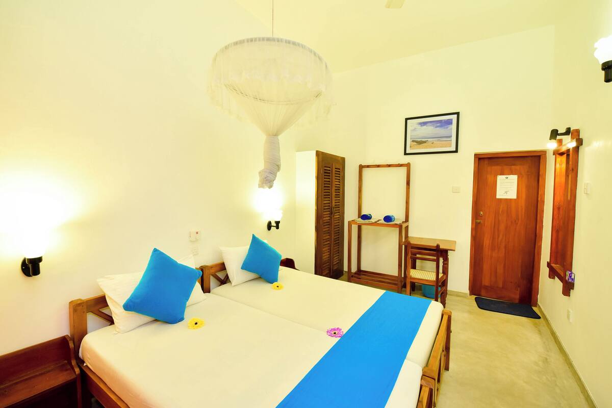 A hotel room with a bed, a wooden bench, a desk, and a wardrobe.
