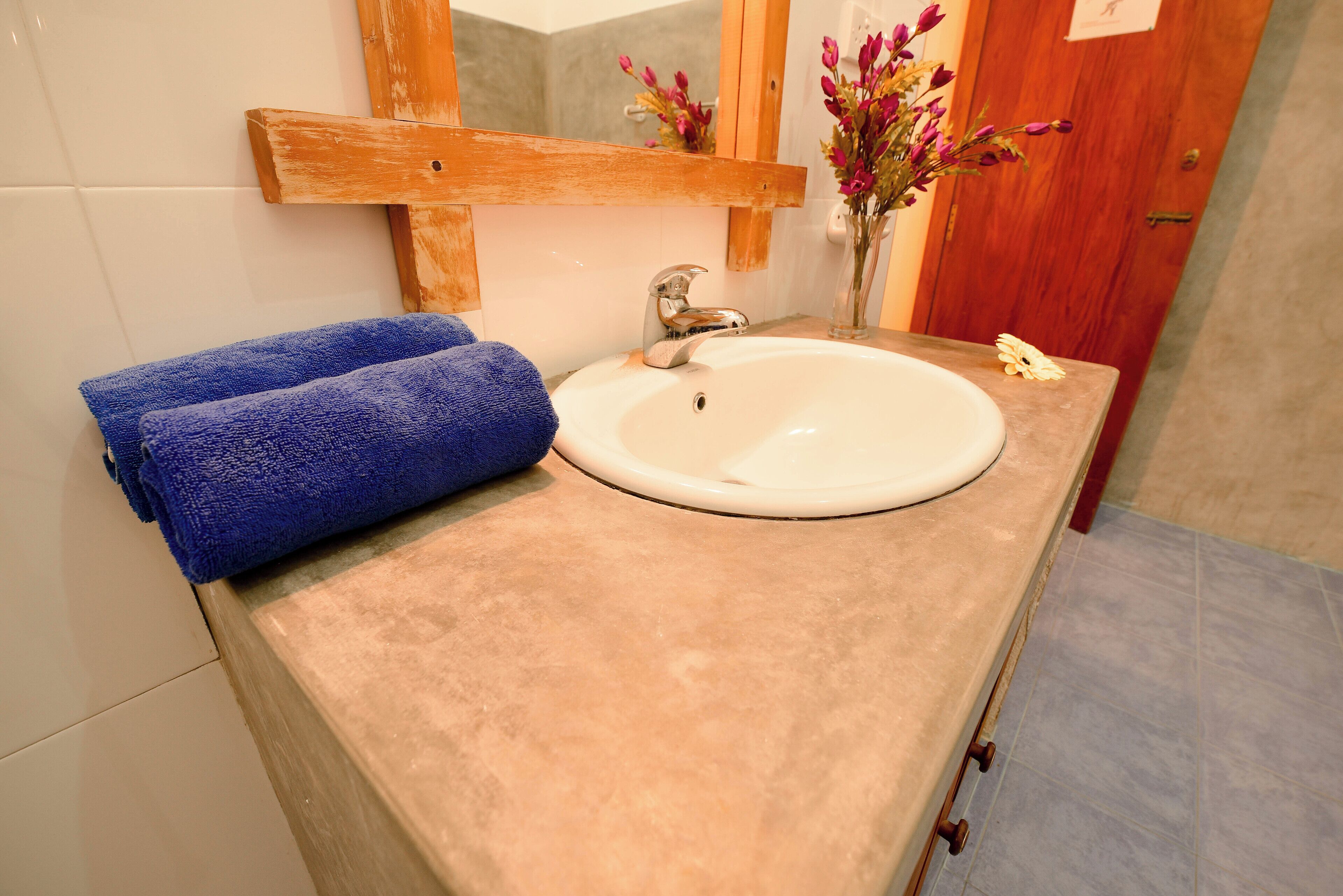 A bathroom with a beige countertop, a white sink, and a wooden-framed mirror.