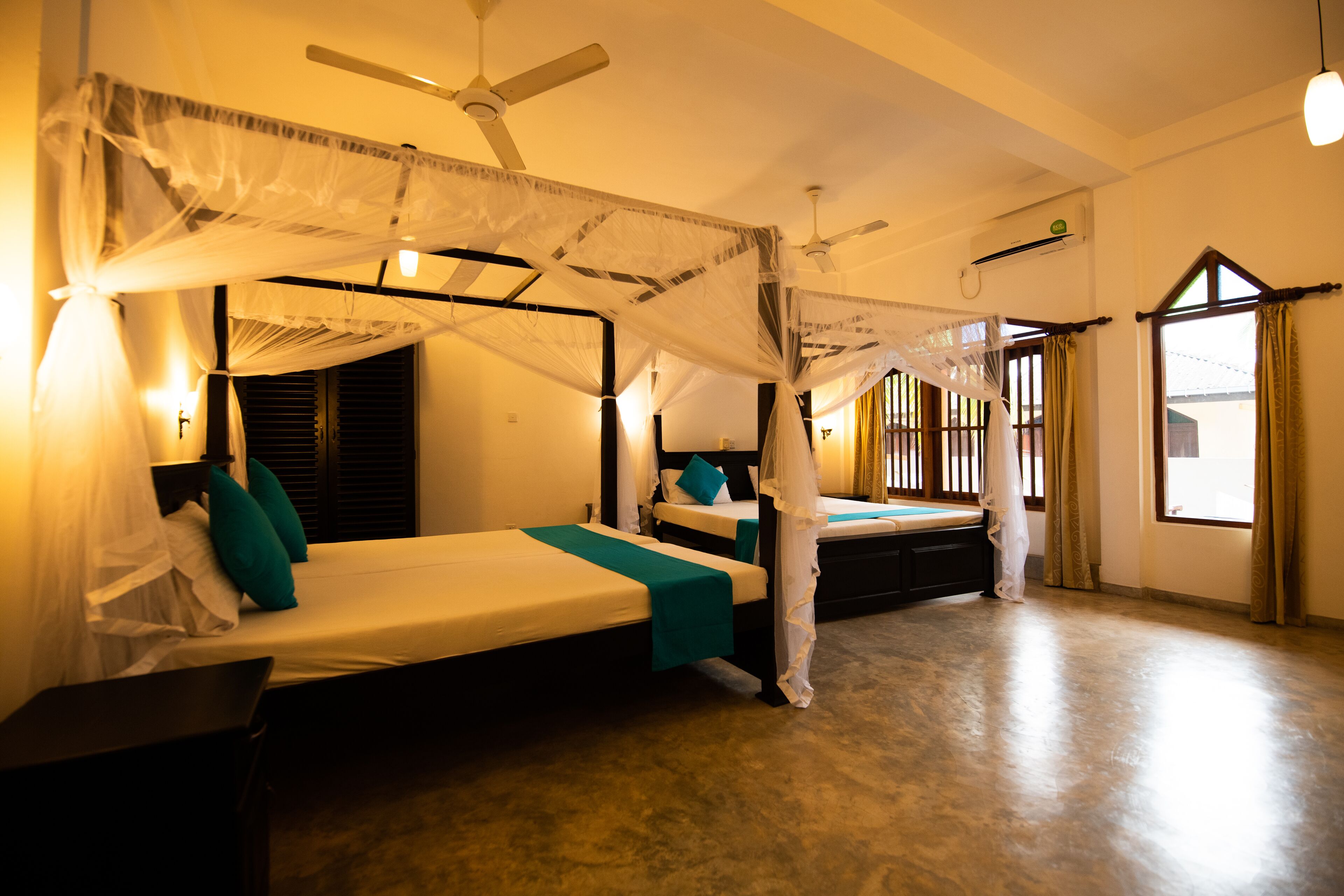 A room with two beds, a ceiling fan, and a window with curtains.