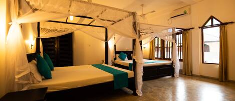 A room with two beds, a ceiling fan, and a window with curtains.
