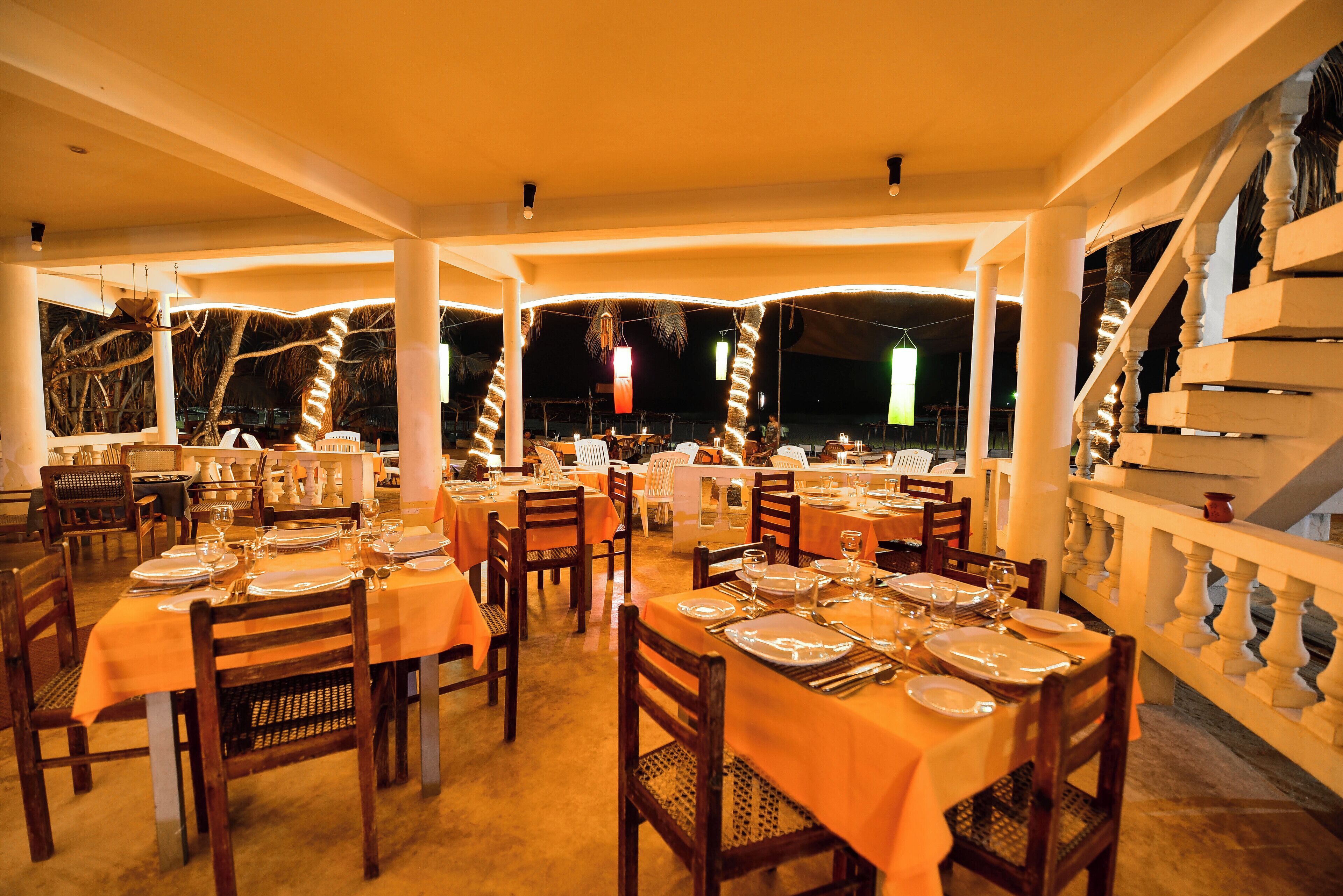 Un restaurante con varias mesas dispuestas para comer, que ofrece un ambiente cálido y vistas al cielo nocturno.