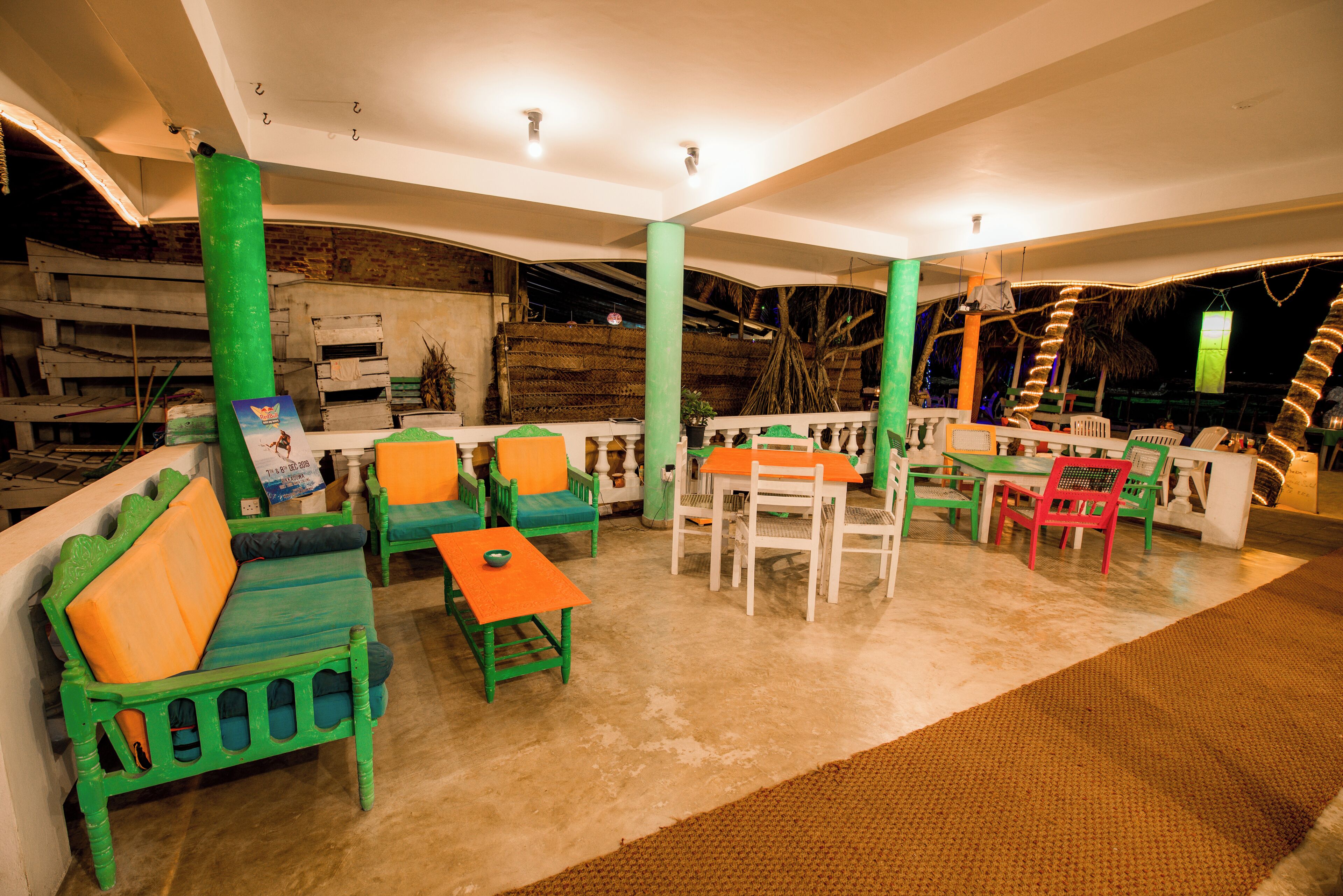 Un amplio espacio interior con mobiliario verde y blanco, incluyendo sofás y sillones, dispuesto alrededor de mesas.